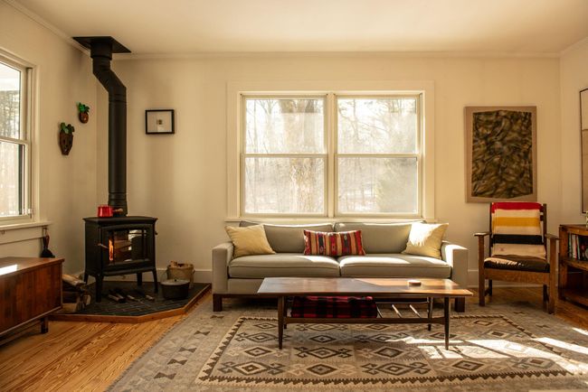 Living room featuring crown molding, light hardwood / wood-style flooring, a wealth of natural light, and a wood stove | Image 5