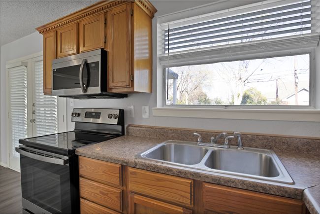 Kitchen with a sink, a textured ceiling, brown cabinetry, and stainless steel appliances | Image 8