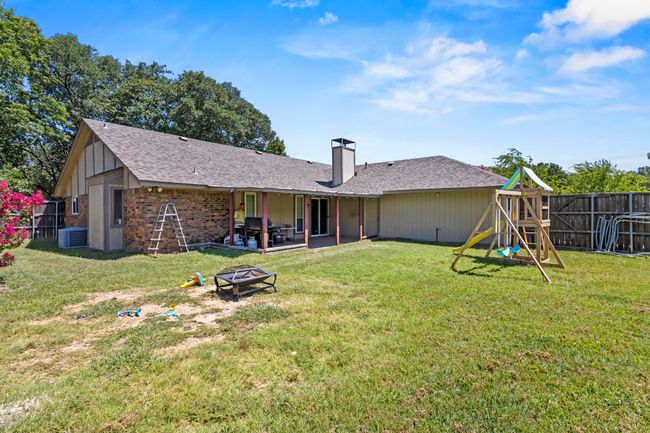 Back of house with a fire pit, a playground, a fenced backyard, a patio, and a chimney | Image 26