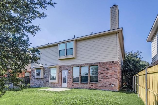Rear view of property with brick siding, a fenced backyard, a chimney, and a patio | Image 21