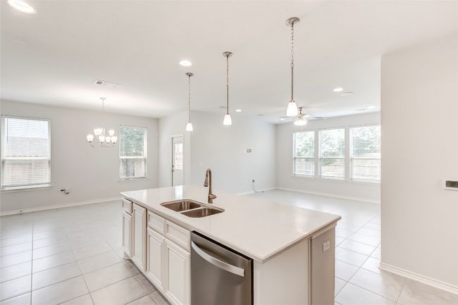 Kitchen featuring dishwasher, light tile patterned floors, a sink, ceiling fan, and a center island with sink | Image 13