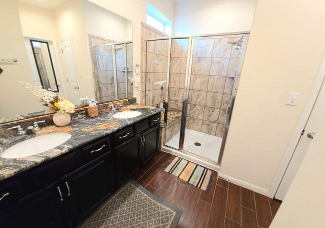 Bathroom featuring a stall shower, double vanity, and wood finished floors | Image 15