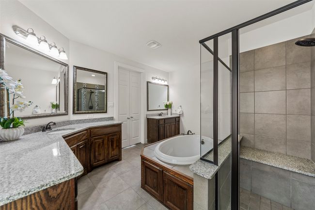 Bathroom featuring a stall shower, tile patterned flooring, a bath, and two vanities | Image 24