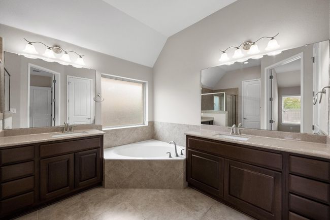 Bathroom with a stall shower, lofted ceiling, two vanities, a garden tub, and tile patterned flooring | Image 14