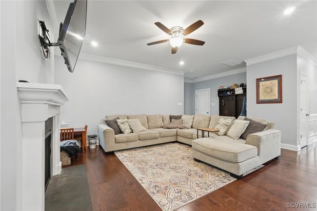 Inviting great room with gas fireplace, ceiling fan, and hardwood floors. | Image 10