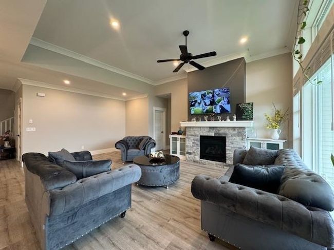 Living area with recessed lighting, wood finished floors, a stone fireplace, baseboards, and ceiling fan | Image 20