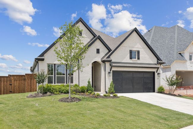French country home with brick siding, driveway, and roof with shingles | Image 5