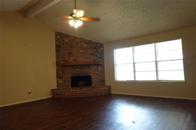 Bright living area with a cozy brick fireplace and expansive backyard views. | Image 32