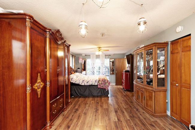 Bedroom with wood finished floors, a textured ceiling, and french doors | Image 15