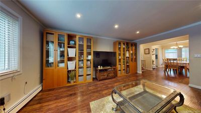 Living room with an inviting chandelier, baseboard heating, ornamental molding, and dark hardwood / wood-style floors | Image 3