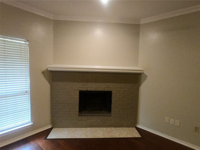 Detailed view of wood finished floors, a brick fireplace, baseboards, and ornamental molding | Image 10