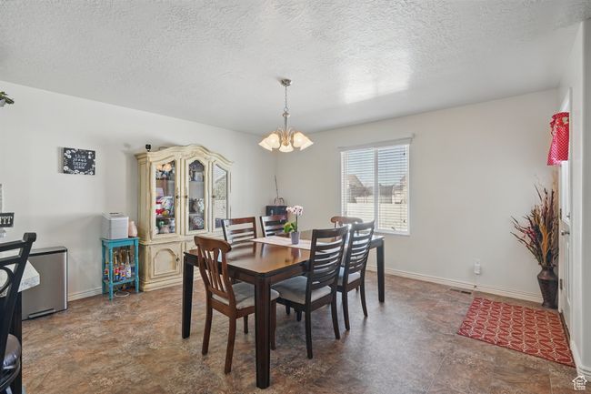 Dining area with baseboards, stone finish floor, an inviting chandelier, and a textured ceiling | Image 19