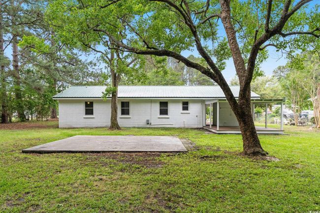 Back of house with a patio, a lawn, metal roof, and concrete block siding | Image 14
