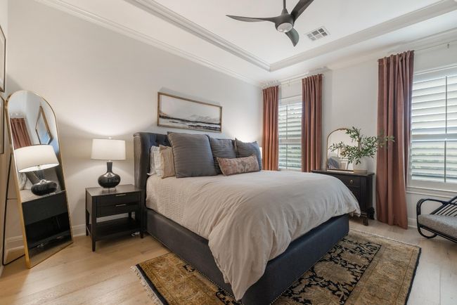 Bedroom featuring multiple windows, light wood-type flooring, a raised ceiling, ceiling fan, and ornamental molding | Image 13