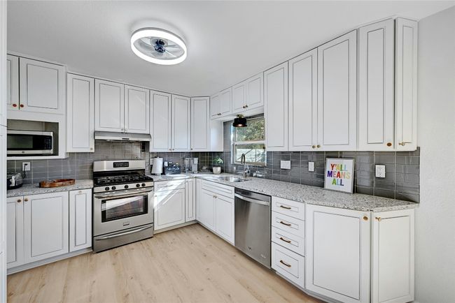 The kitchen is complete with a light fixture/ceiling fan, granite countertops, and plenty of cabinet space for all of your kitchen needs. | Image 12