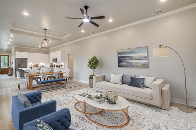 Living room with visible vents, crown molding, baseboards, light wood finished floors, and a tray ceiling | Image 9