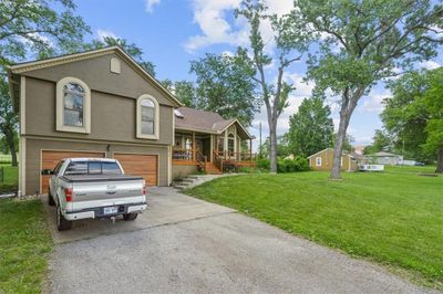 Tri-level home featuring a front yard, a porch, and a garage | Image 2