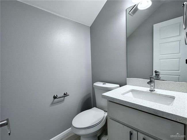 Half bathroom with visible vents, toilet, vaulted ceiling, and vanity | Image 9