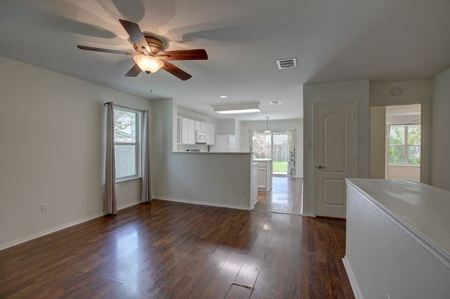 Open concept living room featuring open to kitchen a ceiling fan, plenty of natural light, and dark wood-style floors | Image 15
