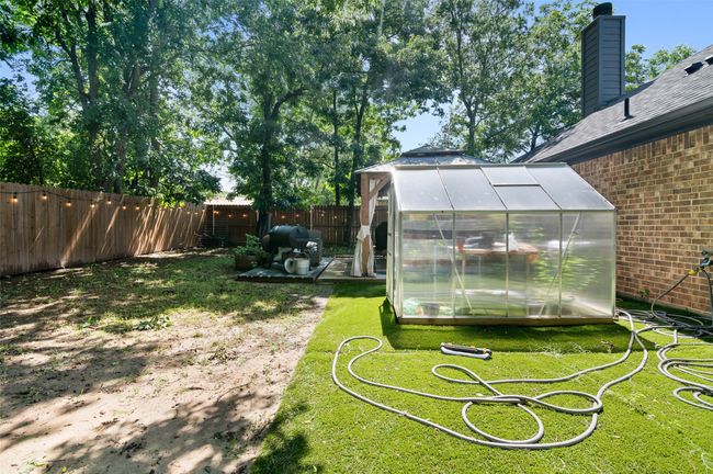 Fenced backyard featuring a greenhouse and an outdoor structure | Image 24