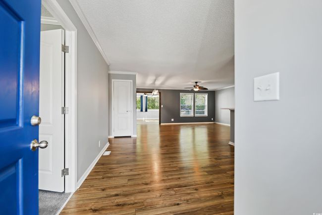 Foyer entrance featuring ceiling fan, crown molding, wood finished floors, a textured ceiling, and baseboards | Image 7