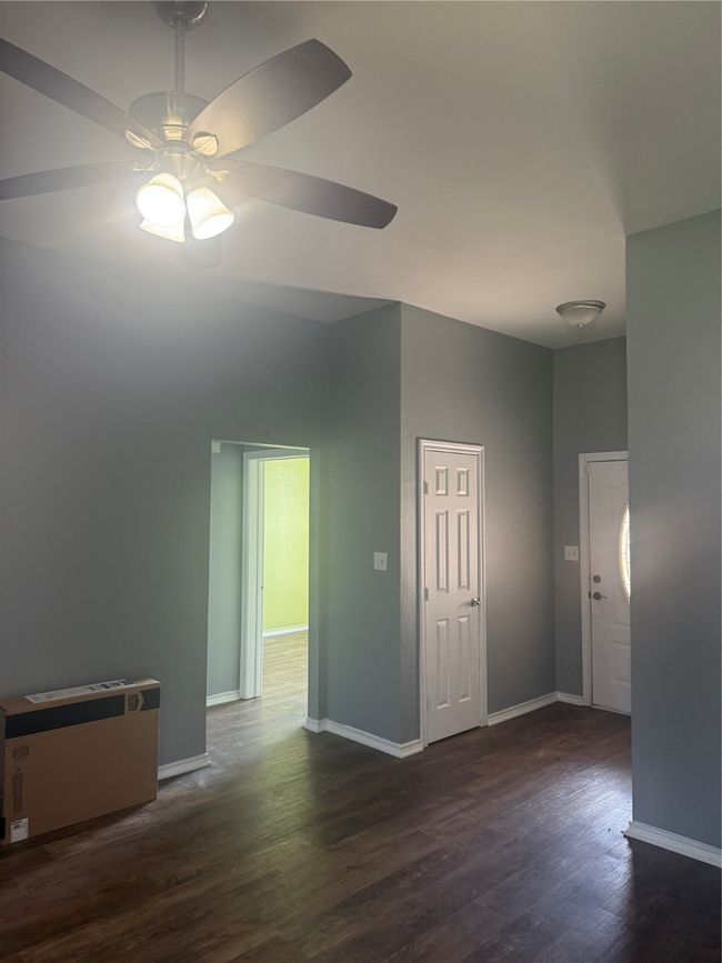Empty room with ceiling fan, baseboards, and dark wood-type flooring | Image 16
