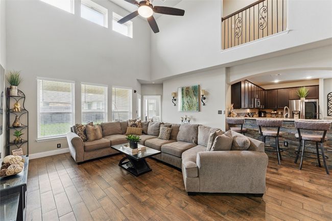 Living area with arched walkways, dark wood-style floors, baseboards, and ceiling fan | Image 9
