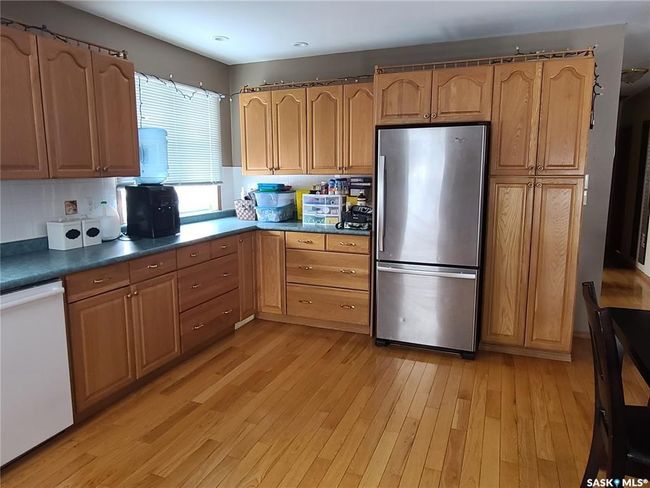 Kitchen with tasteful backsplash, light hardwood / wood-style floors, stainless steel refrigerator, and white dishwasher | Image 8