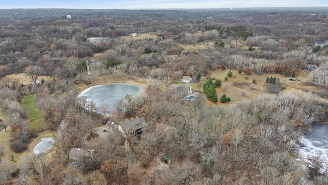 Wider view looking west showing that property extends west beyond the large pond to Coffee Trail. Shows the mixture of lawns, woods, mature trees, and landscaping with horse paddock and run in shelter shown in foreground. | Image 66