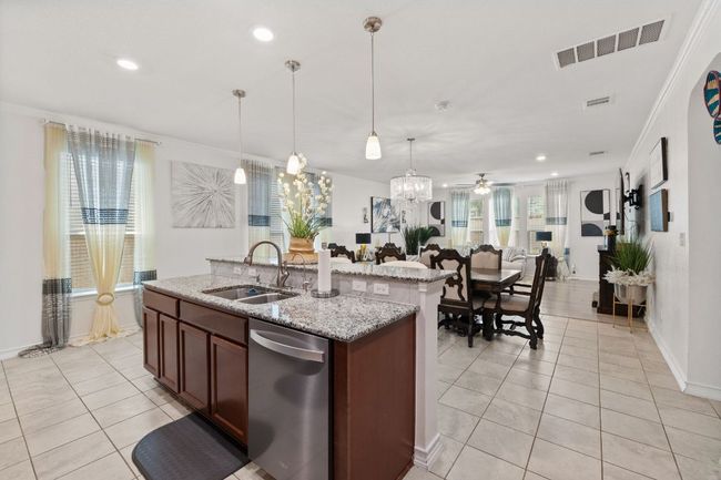 Kitchen featuring dishwasher, light tile patterned floors, open floor plan, crown molding, and a kitchen island with sink | Image 12