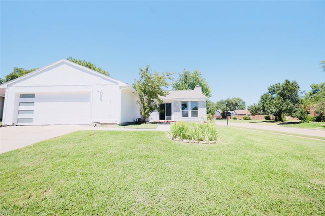 Ranch-style house featuring concrete driveway, a garage, a front yard, and a chimney | Image 37