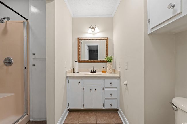 Full bathroom with tile patterned floors, a stall shower, vanity, baseboards, and ornamental molding | Image 11