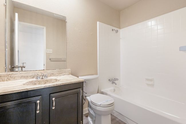 Bathroom with a textured wall, shower / bathtub combination, vanity, and wood finished floors | Image 19
