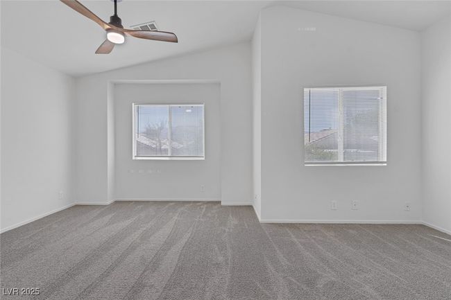 Carpeted spare room featuring lofted ceiling, plenty of natural light, and a ceiling fan | Image 24