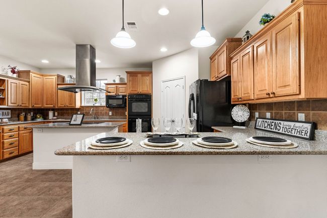 Kitchen with visible vents, open shelves, a peninsula, black appliances, and island range hood | Image 9