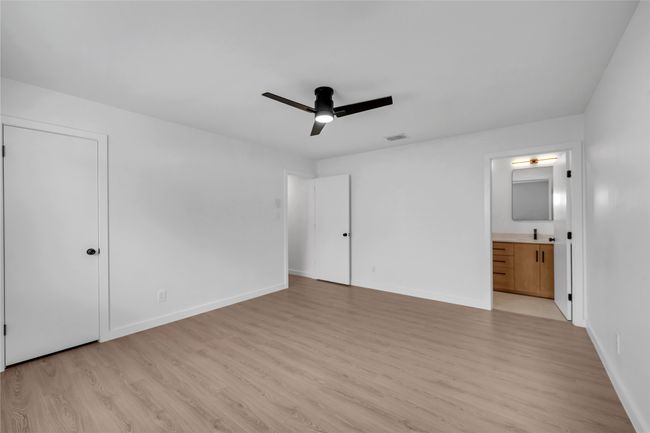 Unfurnished bedroom with light wood finished floors, baseboards, connected bathroom, and ceiling fan | Image 24