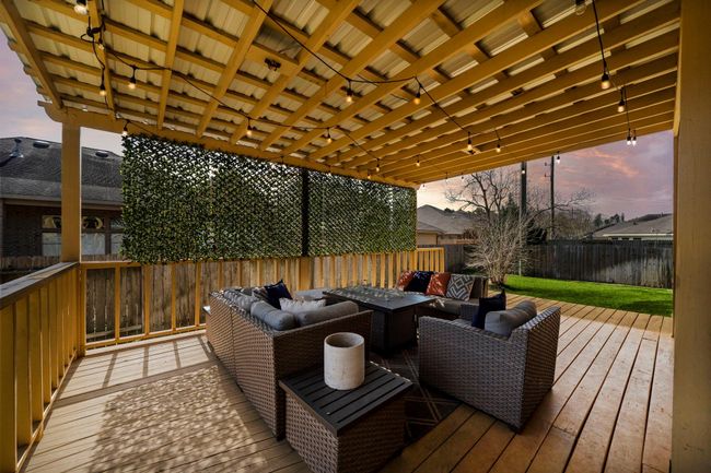 Covered patio with a pergola features a spacious seating area ideal for outdoor entertaining. Enjoy the wood decking and lush green space, creating an inviting extension of the home's living areas. | Image 6