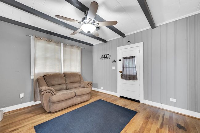 Living area with beamed ceiling, wood finished floors, a ceiling fan, and baseboards | Image 14