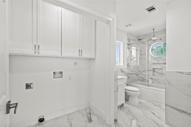 The laundry room is on main level and check out the tile work and custom cabinetry | Image 14