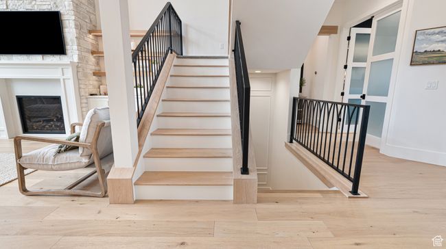Stairs featuring a glass covered fireplace, wood finished floors, and baseboards | Image 9