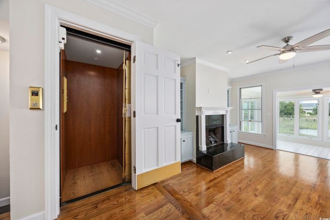 Unfurnished living room with a ceiling fan, wood finished floors, elevator, ornamental molding, and baseboards | Image 33