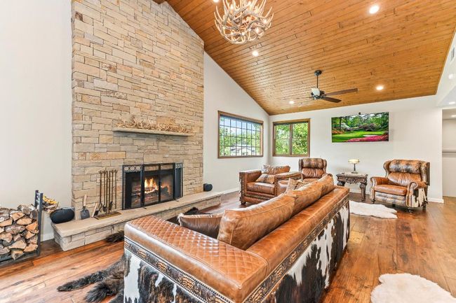 Living area featuring wood ceiling, wood-type flooring, a stone fireplace, ceiling fan, and recessed lighting | Image 5