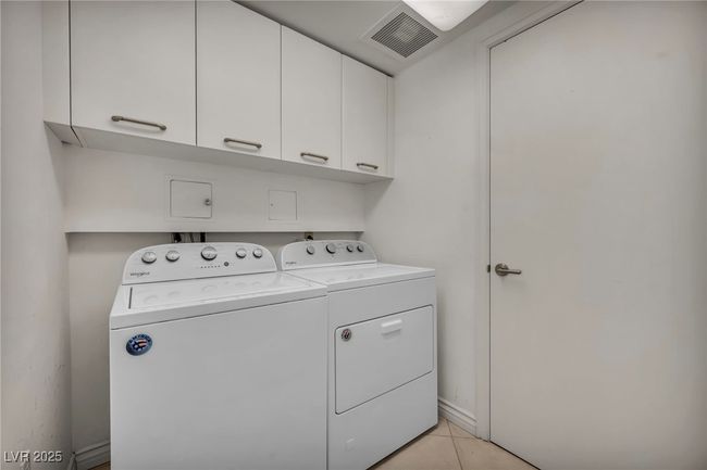 Laundry room featuring cabinet space, independent washer and dryer, visible vents, and light tile patterned floors | Image 14