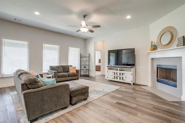 Living room featuring a ceiling fan, healthy amount of natural light, a tiled fireplace, wood finished floors, and recessed lighting | Image 10