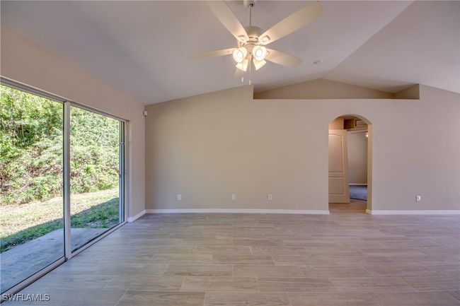 Unfurnished room featuring a wealth of natural light, arched walkways, vaulted ceiling, and a ceiling fan | Image 17