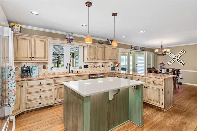 Kitchen featuring a breakfast bar, pendant lighting, a center island, kitchen peninsula, and light wood-type flooring | Image 11