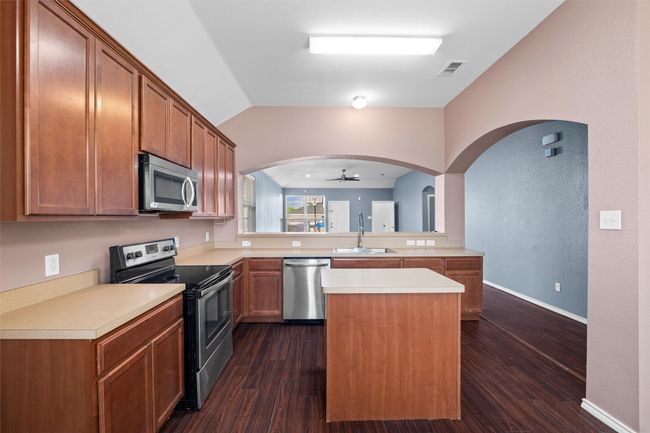 Kitchen featuring a ceiling fan, vaulted ceiling, light countertops, a sink, and stainless steel appliances | Image 23