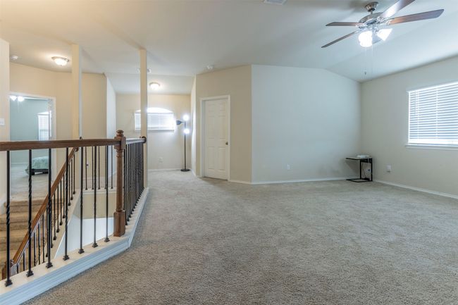 Carpeted empty room featuring baseboards, ceiling fan, vaulted ceiling, and a wealth of natural light | Image 23