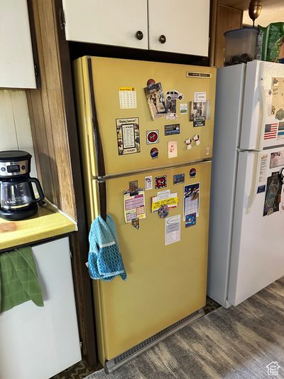 Kitchen featuring white refrigerator, dark wood-type flooring, white cabinetry, and stainless steel refrigerator | Image 3