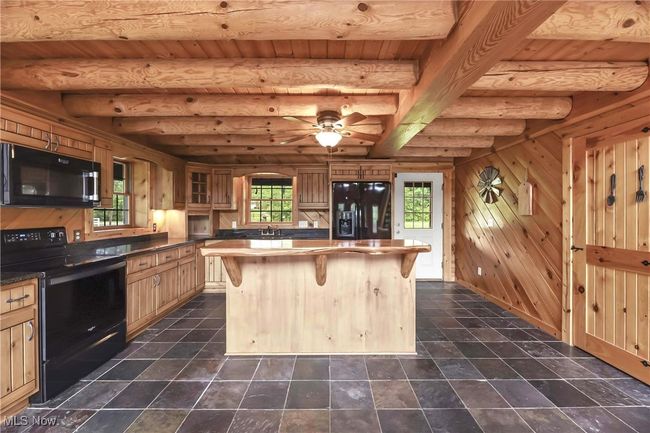 Kitchen with black appliances, black granite counters, center island and slate floors. | Image 4